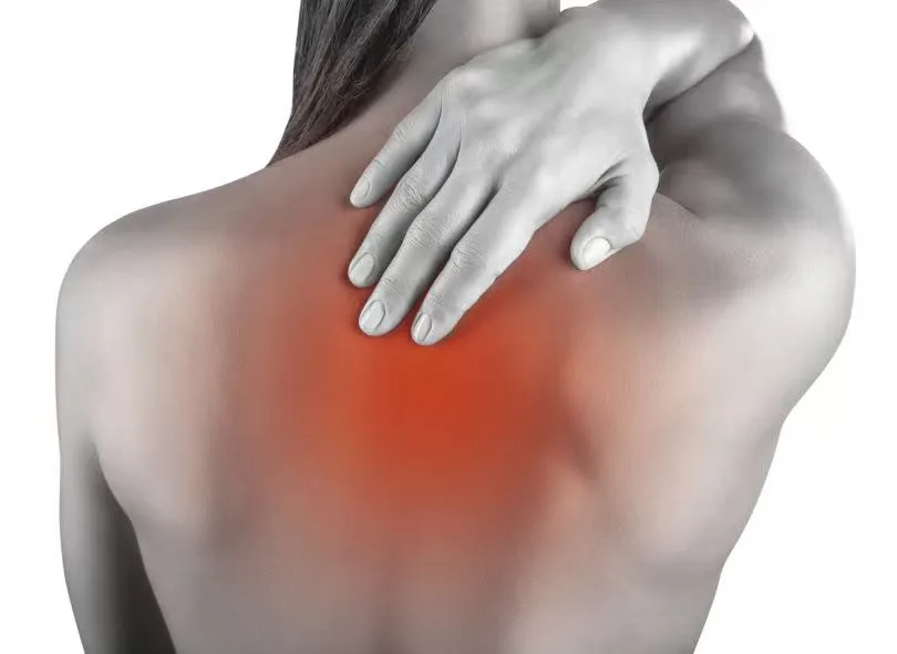A woman reaching to touch the area between her shoulder blades, highlighted in red to show pain